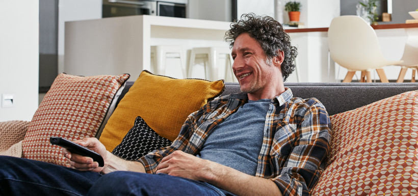 A middle aged man smiling while watching TV